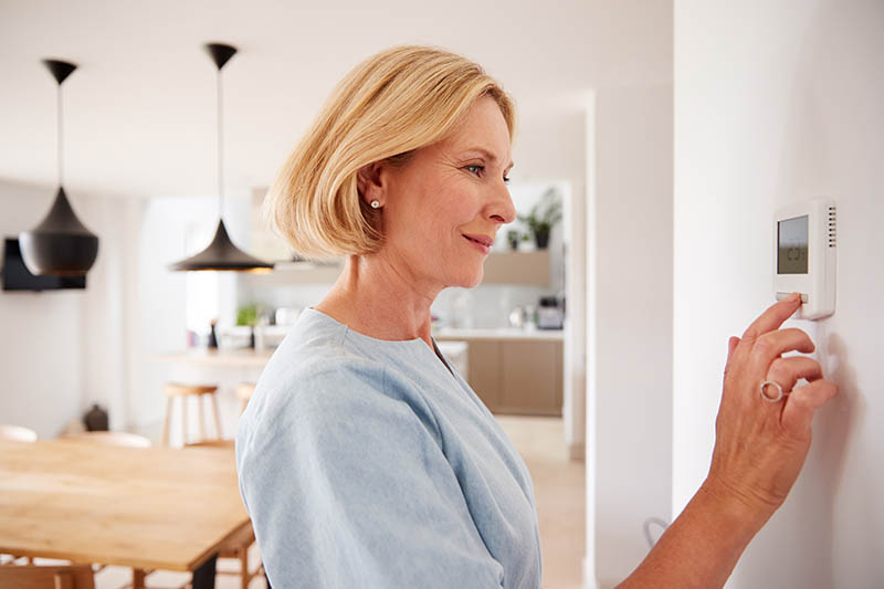 Woman adjusting house thermostat.