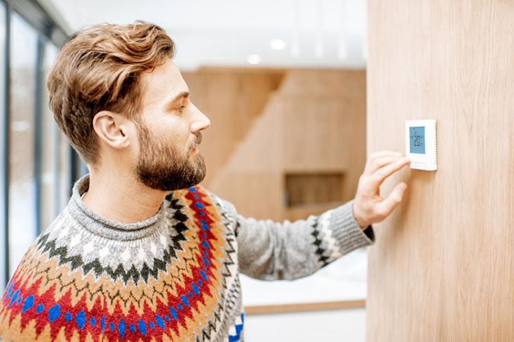 Man adjusting a thermostat.