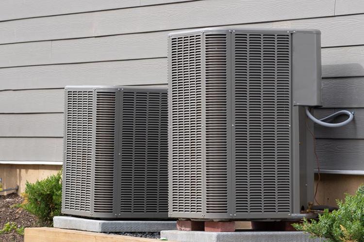 Two air conditioning units beside a house.