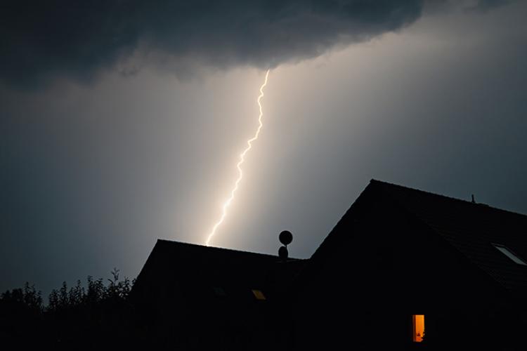 Lightning strike over a house roof.