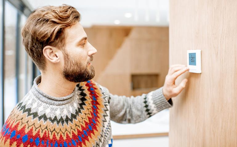 Man adjusting a thermostat.