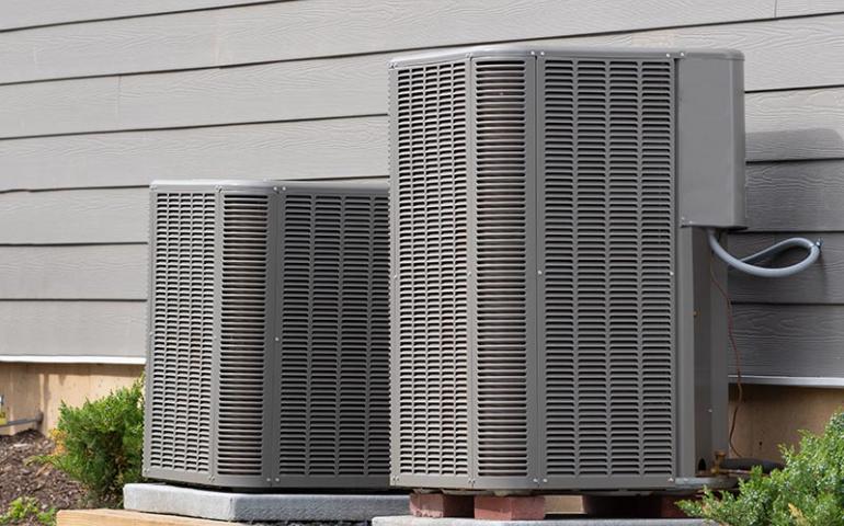 Two air conditioning units beside a house.