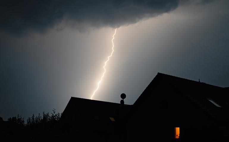 Lightning strike over a house roof.