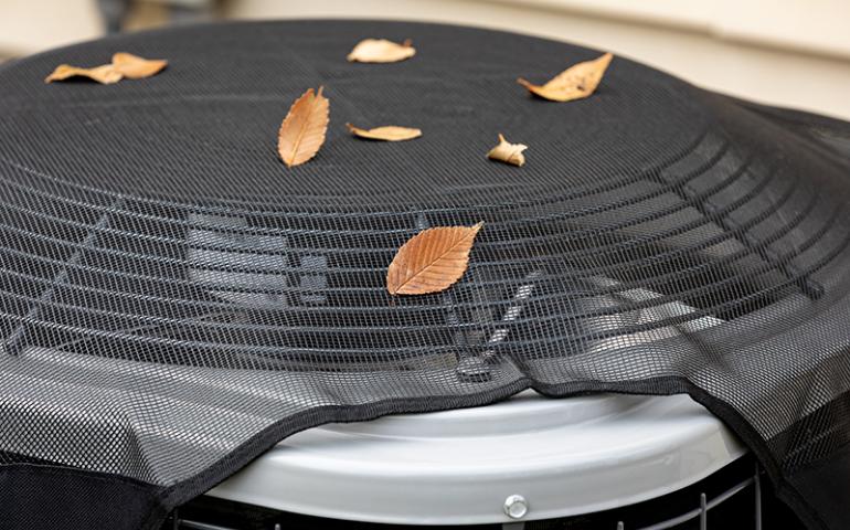 Air conditioning unit with fall leaves on it.