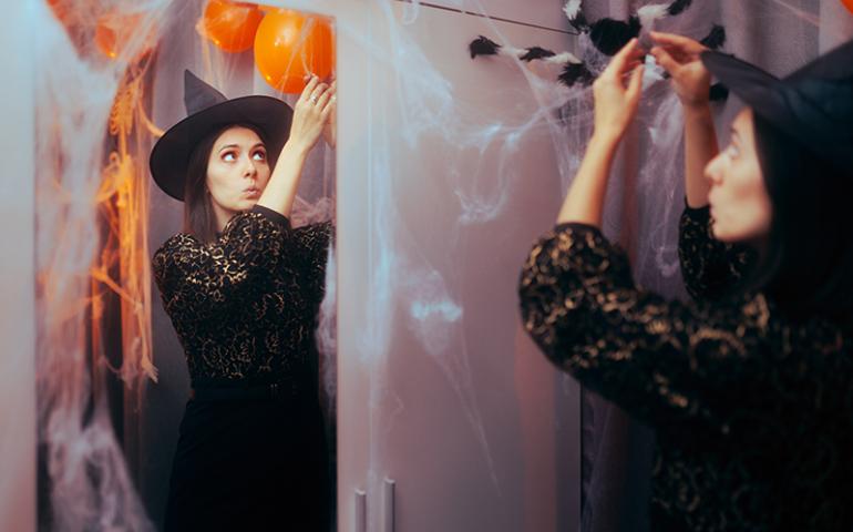 Woman putting up fake spiderweb halloween decorations