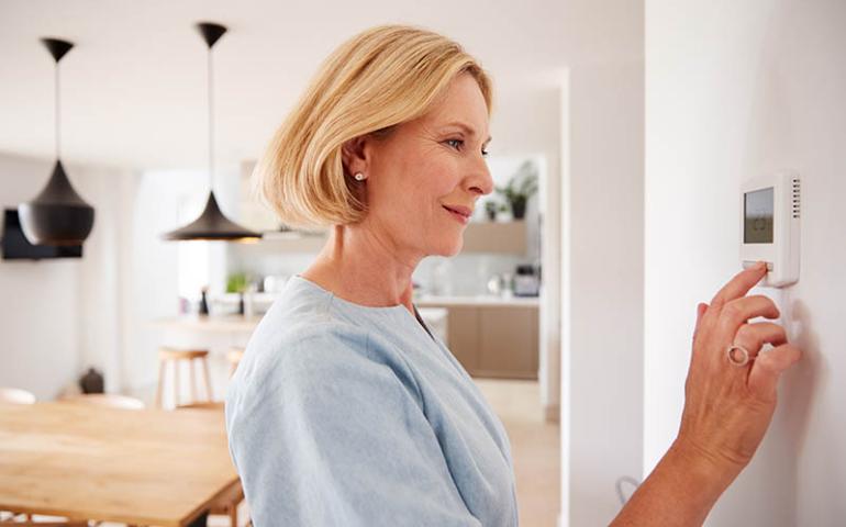 Woman adjusting house thermostat.