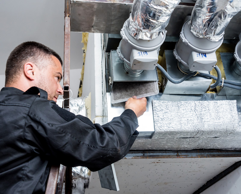 HVAC technician checking the ventilation in a HVAC unit.