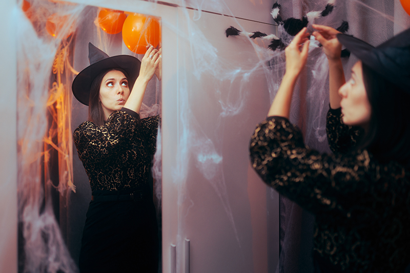 Woman putting up fake spiderweb halloween decorations