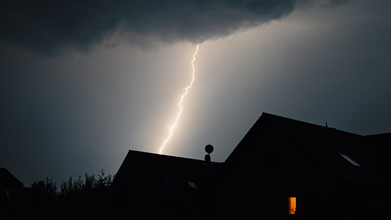 Lightning strike over a house roof.